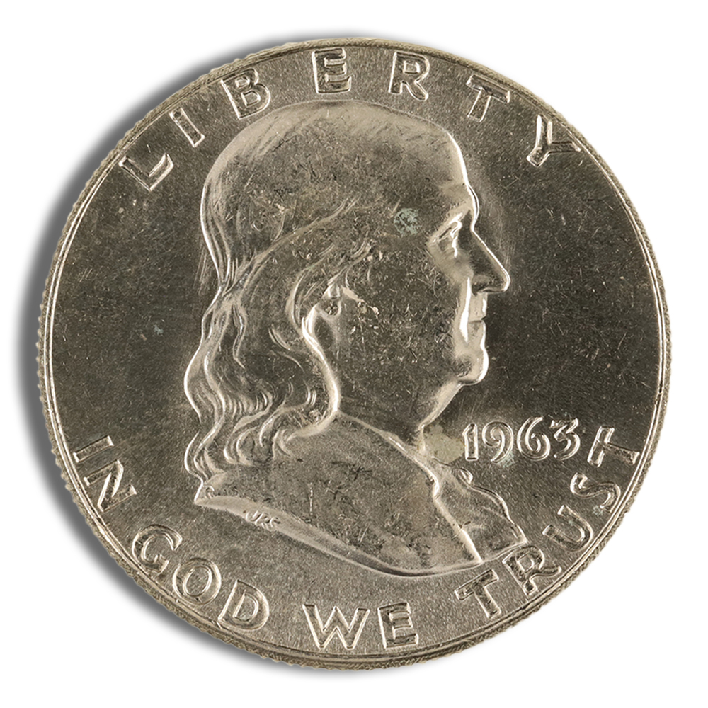 Close-up of a 1963 Franklin half dollar coin featuring the profile of Benjamin Franklin, with inscriptions "LIBERTY" and "IN GOD WE TRUST." The coin's metallic surface displays wear and age, highlighting its historical significance in American numismatics.
