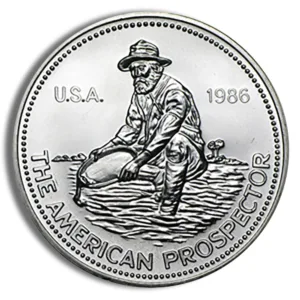 American Prospector coin featuring a miner panning for gold, minted in 1986. The design showcases the miner in a traditional outfit, symbolizing the gold rush era in the USA.