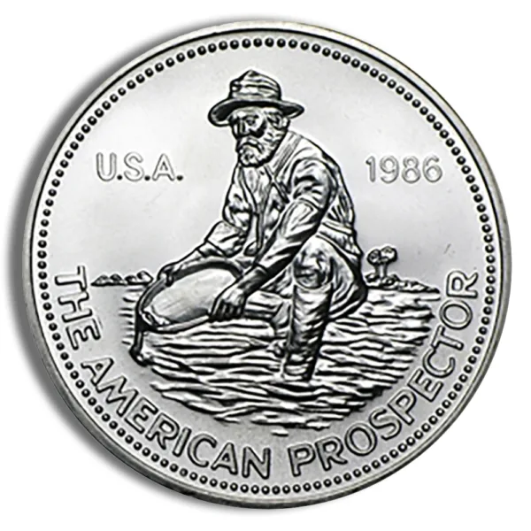American Prospector coin featuring a miner panning for gold, minted in 1986. The design showcases the miner in a traditional outfit, symbolizing the gold rush era in the USA.